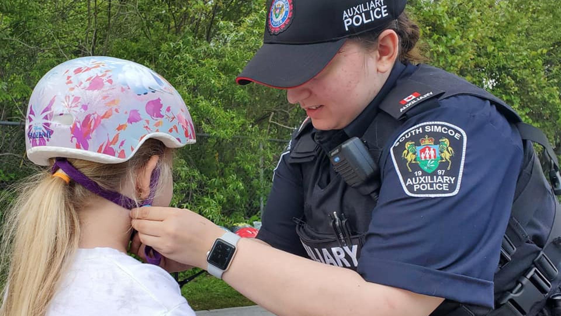 Police officer helping young girl with bike helmet