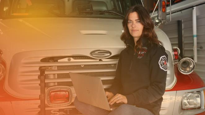 Woman with a laptop sitting on top of a fire truck