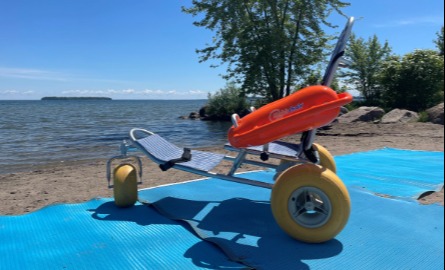 Beach wheelchair on accessibility mat on beach facing water