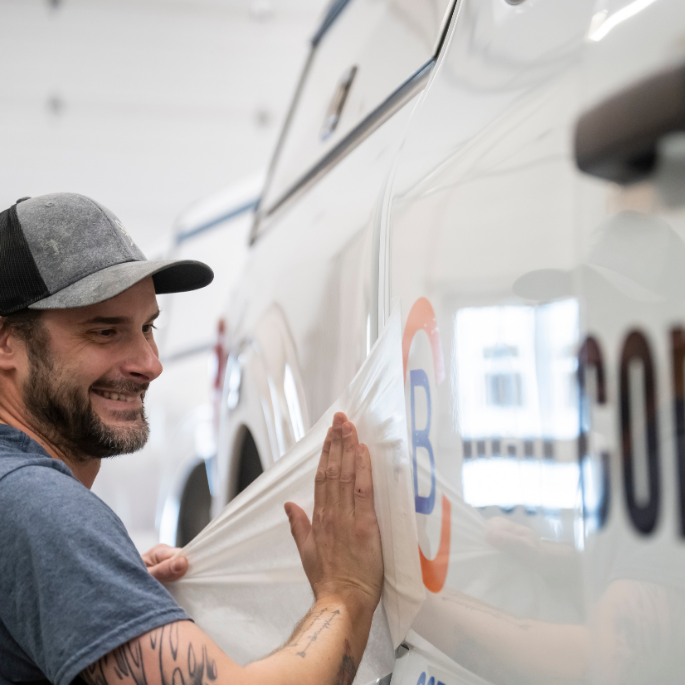 Employee at local business, signz n' designz, installing signage on a company truck.