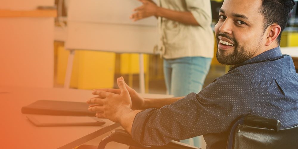 Man in wheelchair at desk smiling