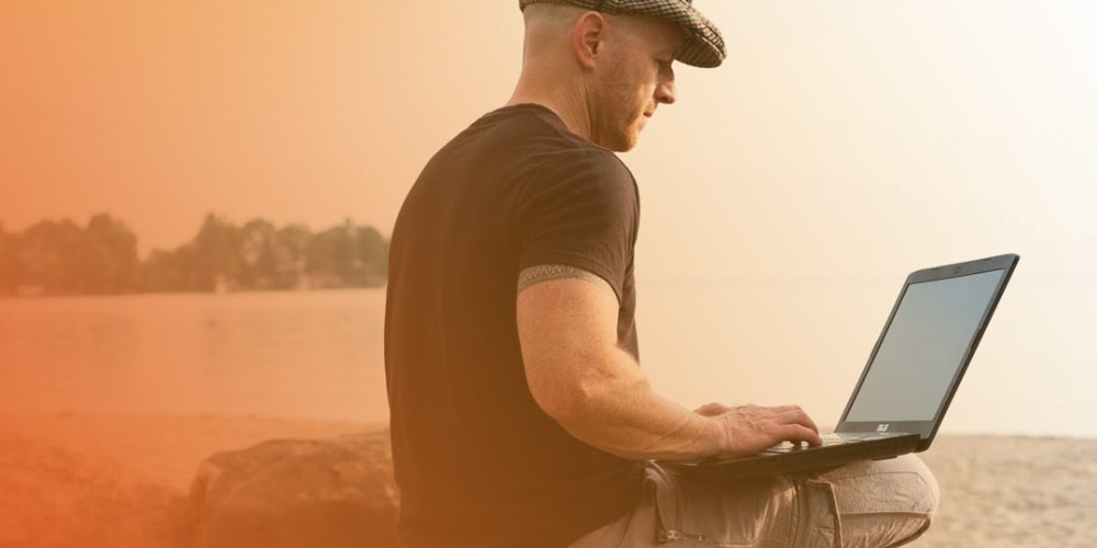 Man working off laptop at beach