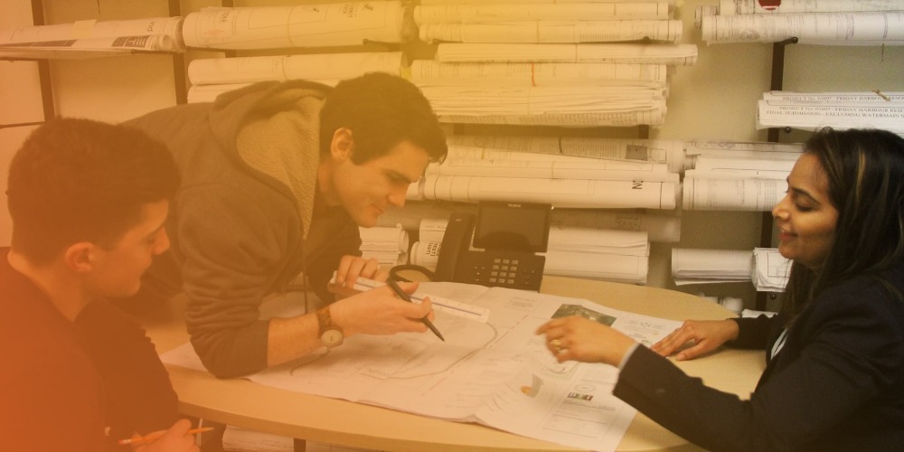 three people discussing plans over a table