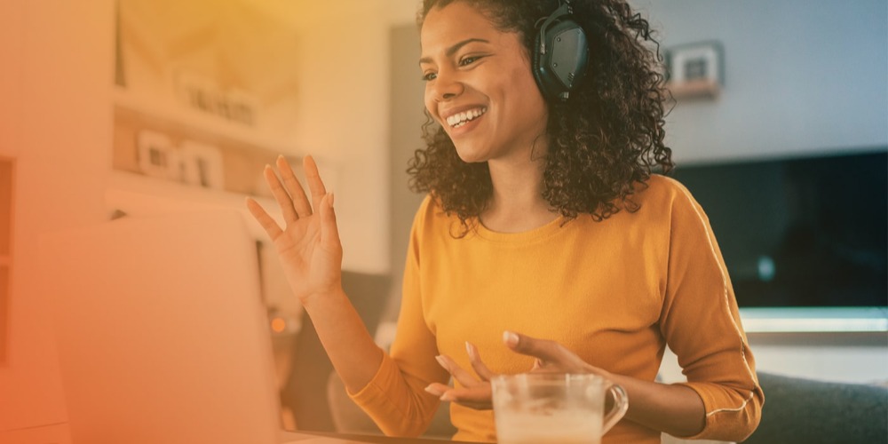 Woman with headset smiling at laptop during virtual meeting