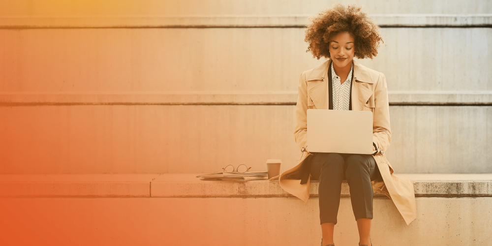 Woman sitting on stairs outside using laptop