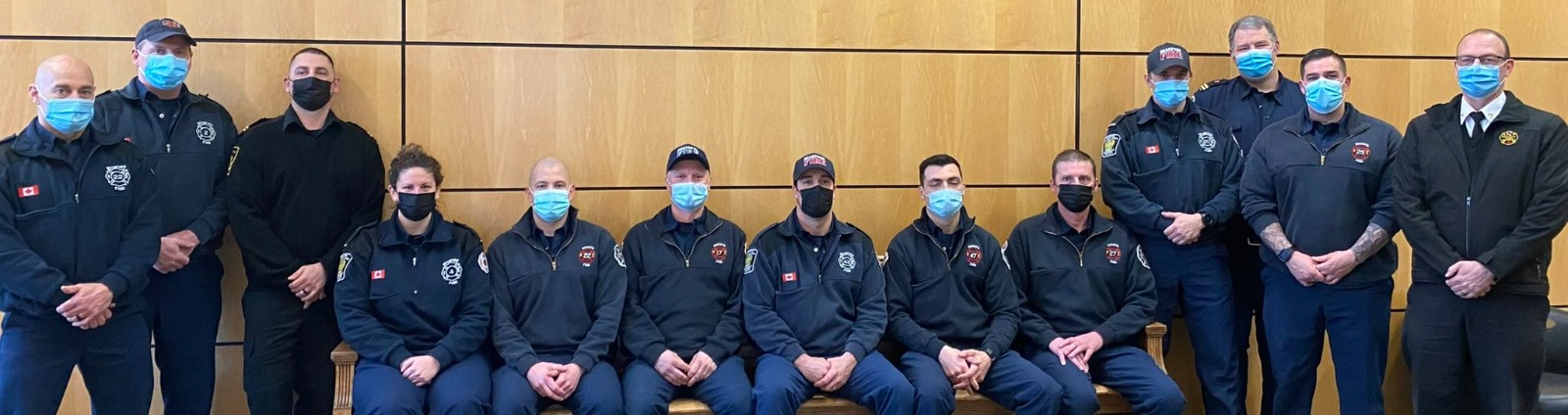 group of firefighters in masks posing for photo sitting down