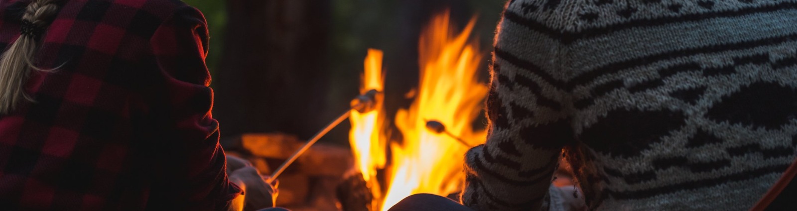 Two people roasting marshmallows over campfire