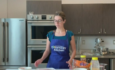 Woman with apron leading cooking class in community kitchen