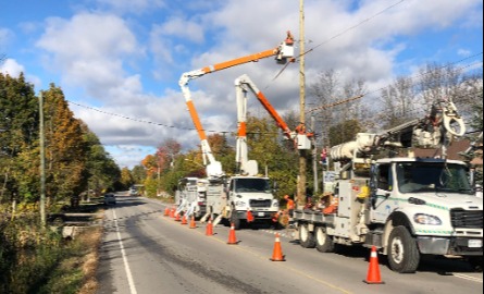 Power crews fixing lines along road