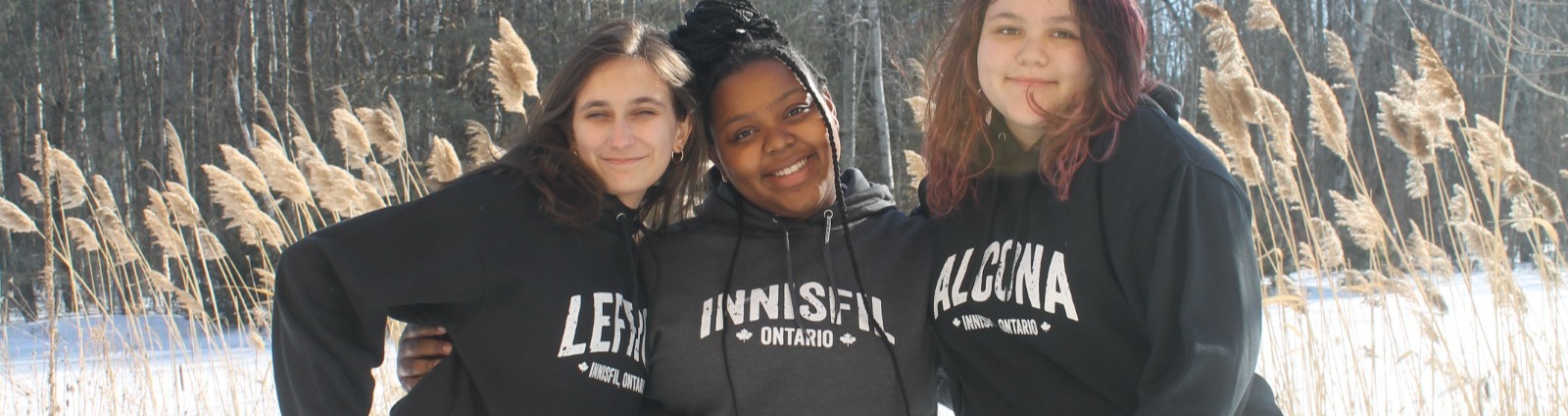 Group of three teen girls wearing hoodies and smiling