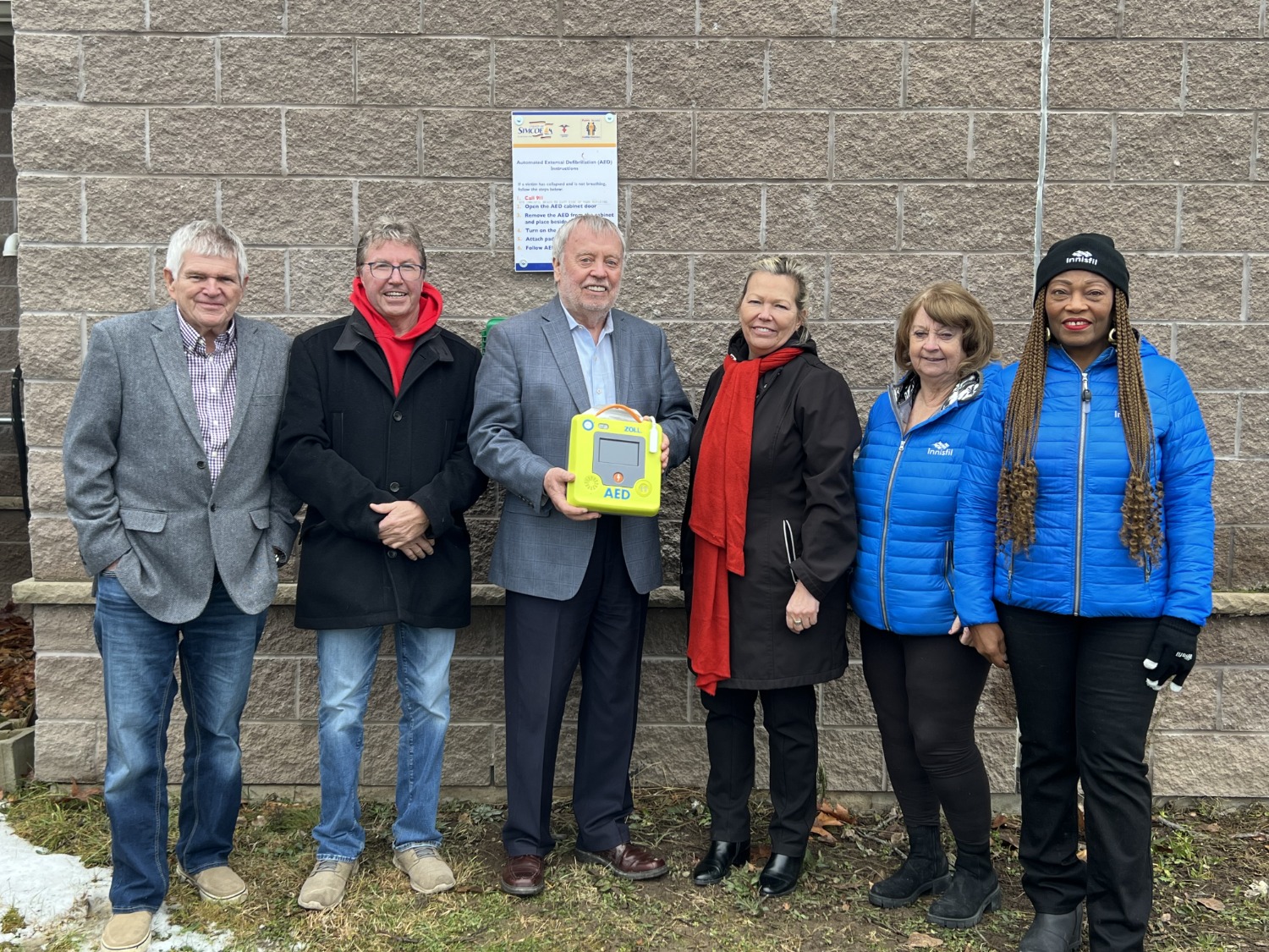 Council members standing with AED unit