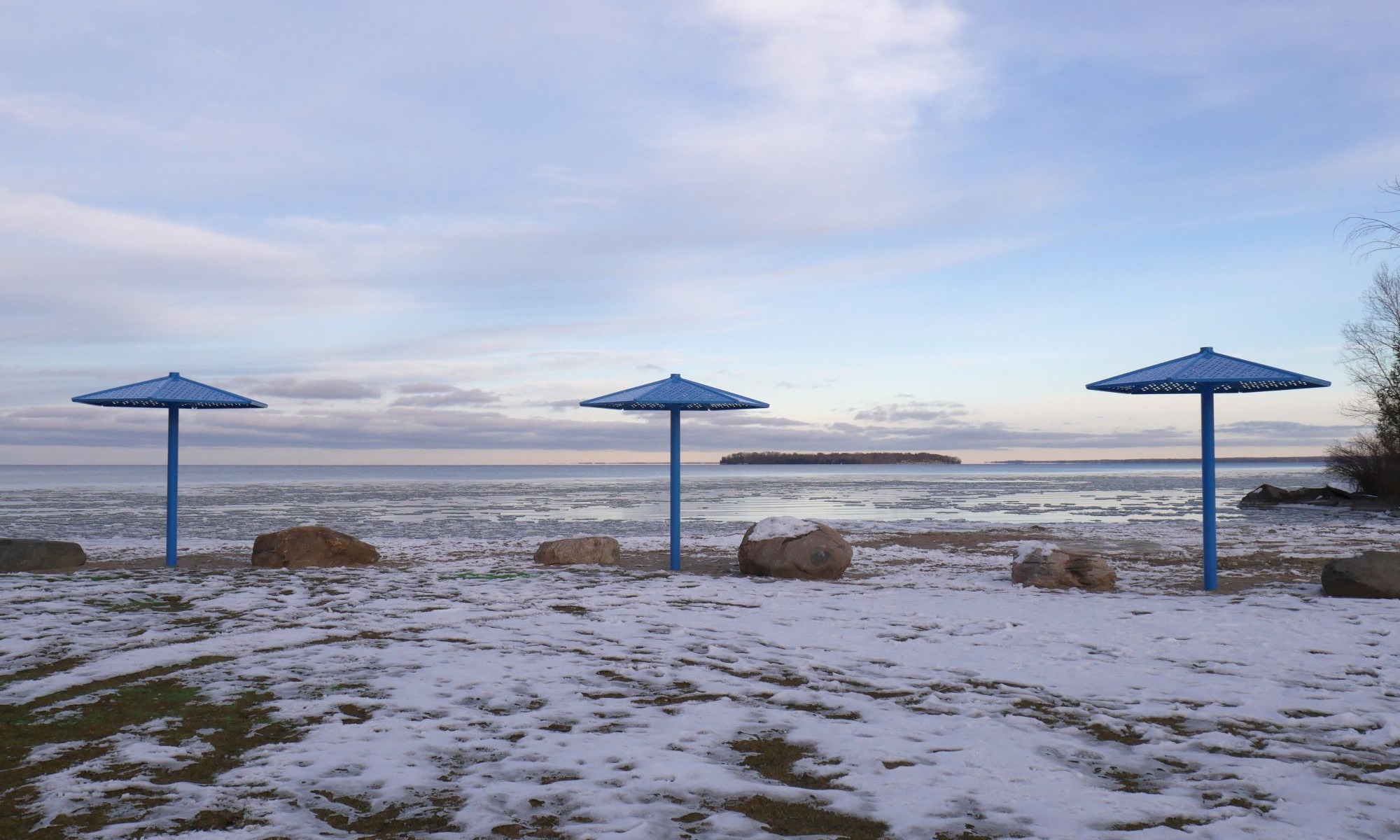 Beach with three blue umbrellas in winter