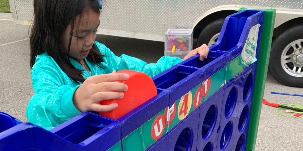 Young girl playing connect 4 outside