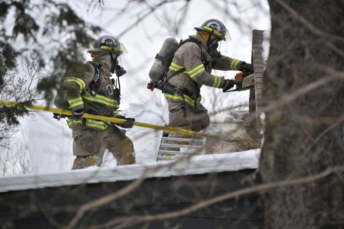 Two firefighters in gear climbing ladder outside