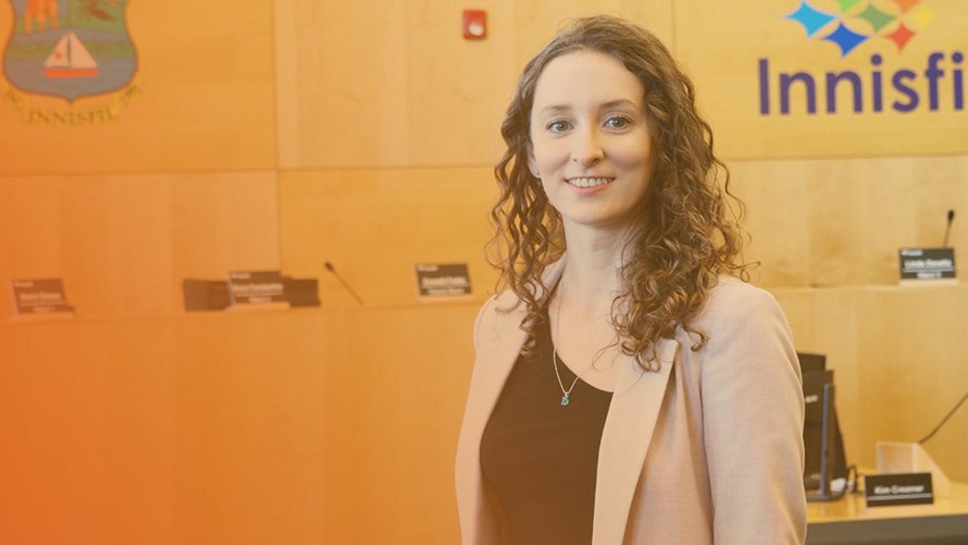 employee standing in council chambers smiling