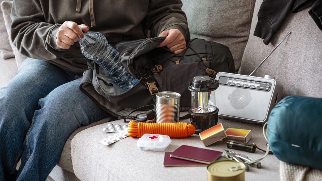 Woman filling emergency backpack with disaster emergency supplies