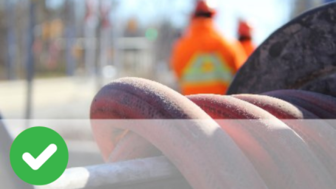 Close up of pipe with workers in the background outside