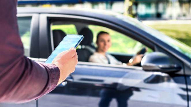 Rideshare passenger looking at phone as driver pulls up on the street