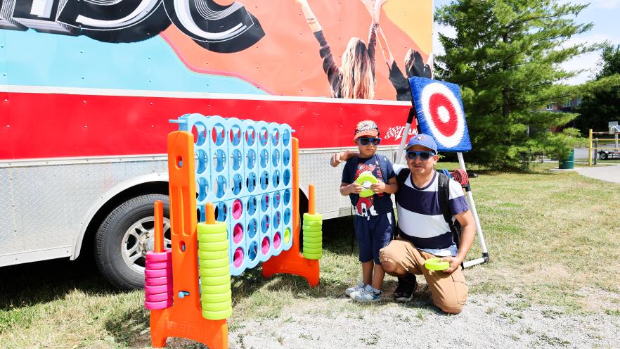 Father and young son posing by a giant game of Connect Four