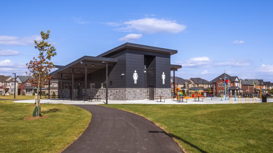 Accessible park building with washroom facilities, covered seating areas, and nearby pathways.