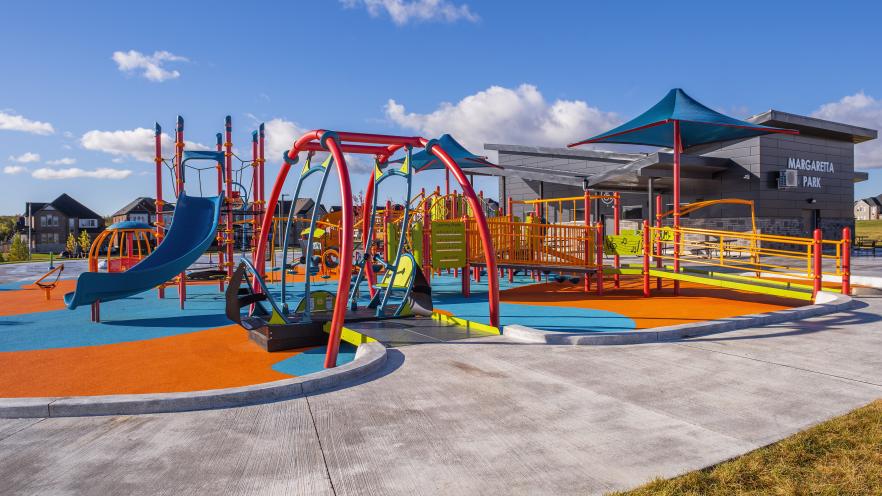 Inclusive playground featuring accessible surfacing, ramps, swings, slides, and sensory play elements at Margaretta Park.