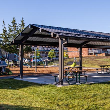 Modern children's playground with slides, swings, and other elements with a suburban neighbourhood in the background